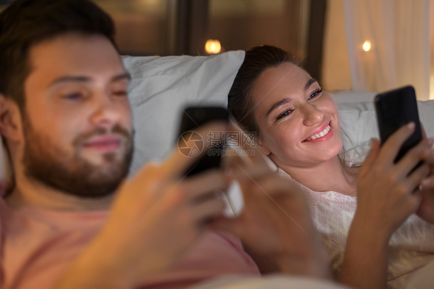 夫妇晚上床上玩手机图片