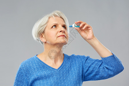 医学,健康视力人的老妇女干眼综合征的肖像用滴灰色背景上老妇女干眼综合征用滴剂背景