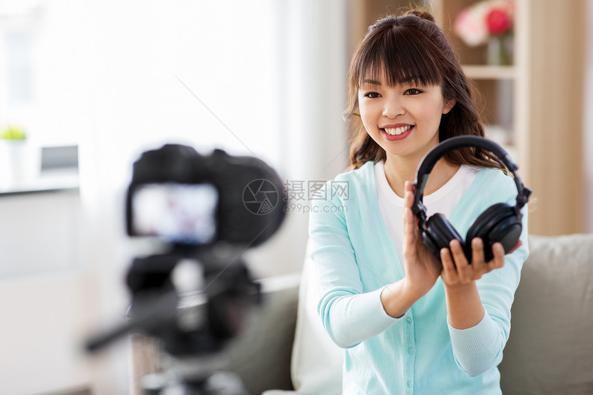 博客,视频博客人的亚洲女博客与相机记录视频审查耳机家带耳机的女博主制作视频博客图片