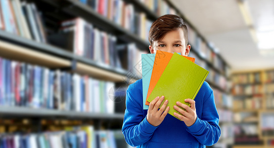 学校教育人的害羞的学生男孩躲图书馆背景的书架上的书后害羞的学生男孩躲图书馆的书后背景图片