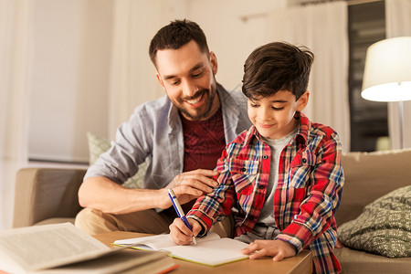 教育,家庭家庭作业的快乐的父亲儿子家里写书笔记本父亲儿子作业图片