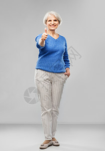 手势老人的微笑的老年女子穿着蓝色毛衣的肖像,灰色微笑的老年女子R竖大拇指幸福的高清图片素材