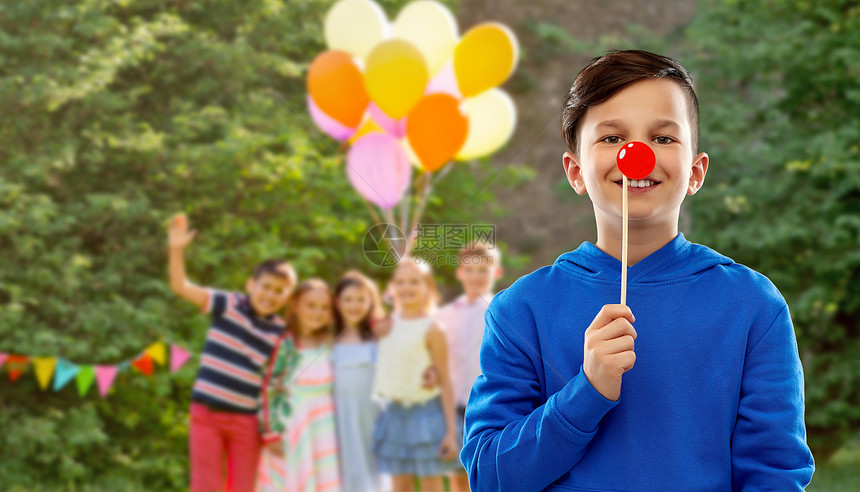 红鼻子日,派道具照片展位微笑男孩蓝色帽衫与小丑鼻子群朋友生日夏季公园背景生日派上红色小丑鼻子的快乐男孩图片