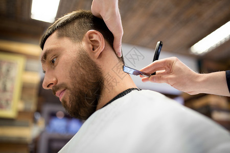 美容人的男客户理发师与直剃须刀剃须颈部头发理发店男人理发师用直剃刀剃头发图片