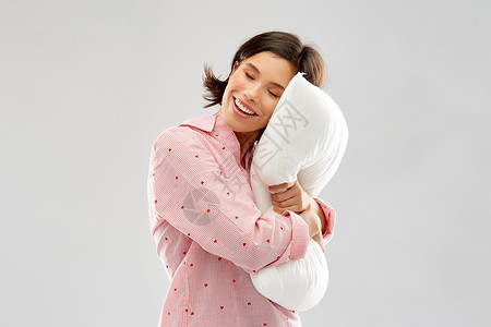 人们睡前的快乐的轻女人睡衣拥抱枕头灰色背景快乐的轻女人睡衣拥抱枕头图片