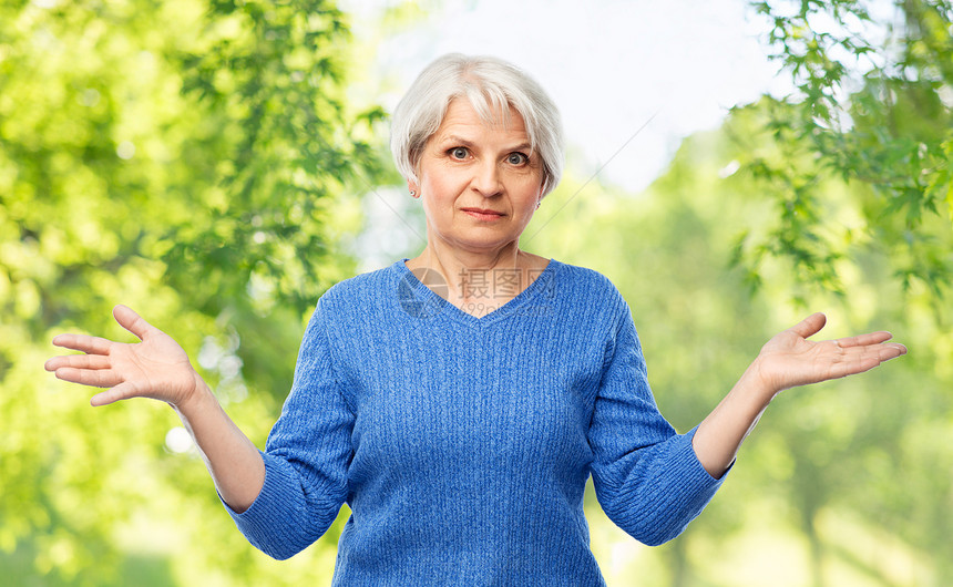 穿着蓝色毛衣的老年女子做出无奈的手势图片