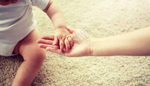 来袭家庭,慈善人的亲密的小婴儿母亲的手把小宝宝妈妈的手关来背景