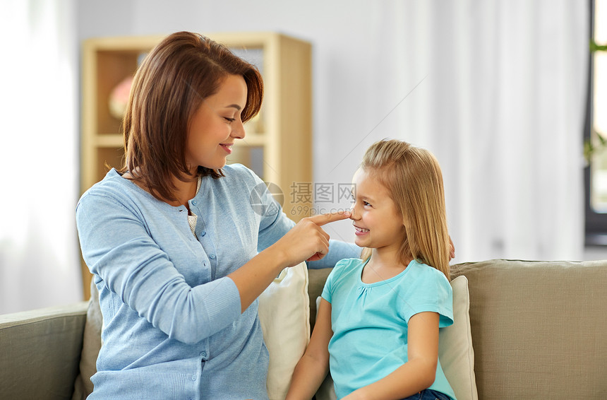 家庭世代人的幸福微笑的母亲女儿坐家里的沙发上母亲女儿坐家里的沙发上图片