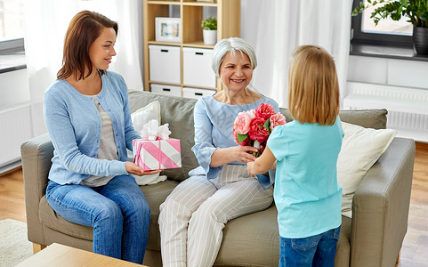家庭世代生日快乐的母亲带着礼品盒女儿家里给祖母送花孙女给祖母送花图片