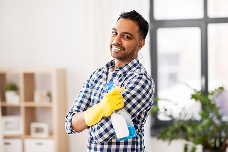 清洁,家务家务微笑的印度男子与洗涤剂家里微笑的印度男人家里用洗涤剂清洗图片