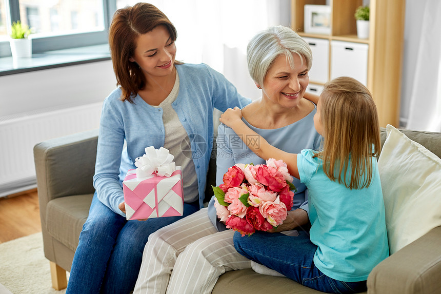 家庭,代生日快乐的母亲带着礼品盒女儿拥抱祖母家孙女拥抱问候祖母图片