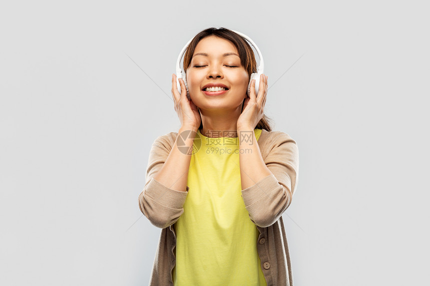 人,技术音频设备的快乐的轻亚洲妇女耳机听音乐灰色背景戴耳机听音乐的亚洲女人图片