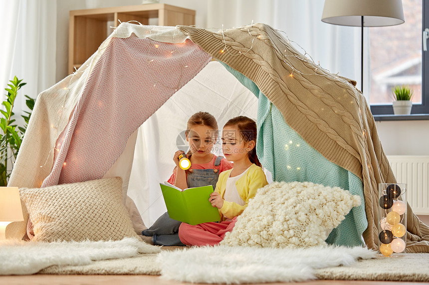 童,潮湿友谊的快乐的女孩阅读书与火炬灯孩子帐篷帐篷家里快乐的女孩家孩子们的帐篷里看书图片