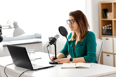 技术,大众媒体人们的戴着麦克风笔记本电脑的眼镜的女人录音室交谈录制播客演播室里麦克风录音播客的女人记录高清图片素材