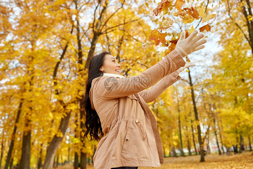 季节人们的快乐的轻女人扔枫叶玩秋天的公园快乐的女人秋天的公园里玩树叶图片