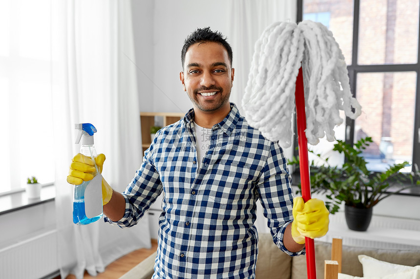 清洁,家务家务微笑的印度男子与拖把洗涤剂家里印度男人家里用拖把洗涤剂清洗图片