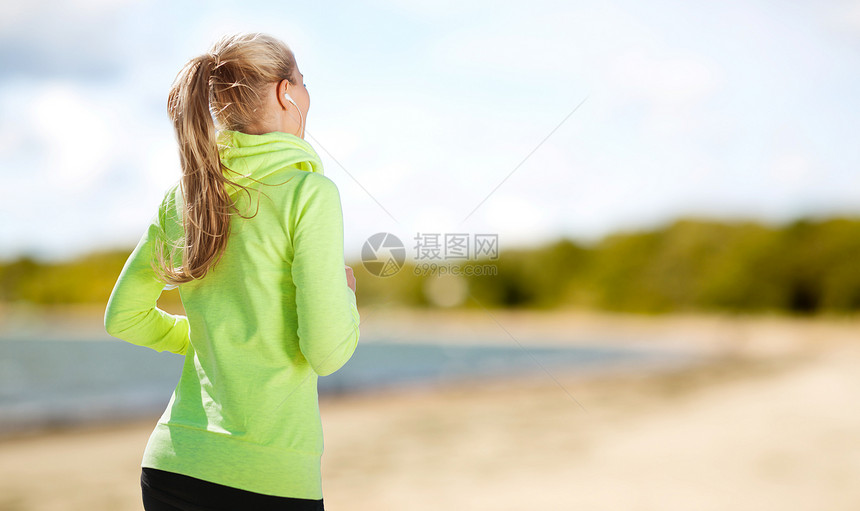 健身,运动健康的生活方式妇女与耳机运行听音乐夏季海滩背景耳机的女人公园跑图片