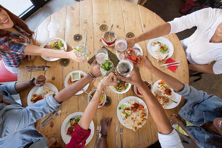 休闲,食物人的群快乐的国际朋友餐厅的桌子上吃碰杯朋友们餐馆吃饭碰杯图片