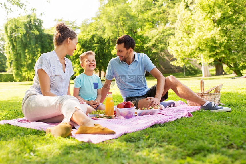 家庭,休闲人的快乐的母亲,父亲小儿子夏季公园野餐快乐的家庭夏天的公园野餐图片