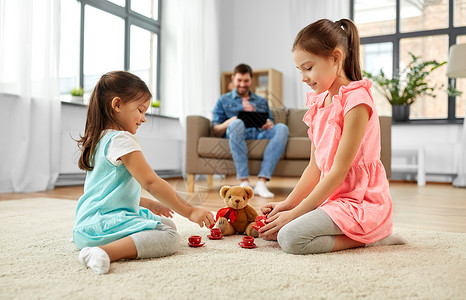 童休闲家庭观念小妹妹家里玩具陶器泰迪熊玩茶话会游戏女孩们家里玩玩具陶器泰迪背景图片