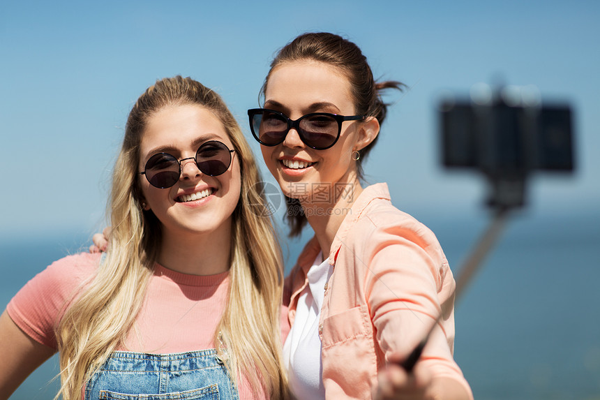 休闲友谊快乐微笑的十几岁女孩最好的朋友太阳镜拥抱拍照智能手机自拍杆海边夏天十几岁的女孩朋友夏天自拍图片