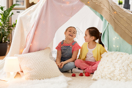 童潮湿的快乐的小女孩玩茶玩具陶器孩子们的帐篷家里小女孩家孩子们的帐篷里玩茶话会背景图片