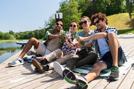 休闲,野餐技术朋友与饮料拍照自拍杆湖墩夏季公园饮料的朋友湖码头自拍干杯高清图片素材