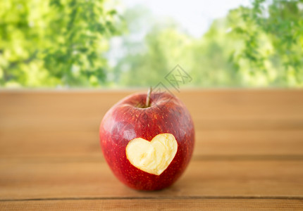 水果,食物健康成熟的苹果,雕刻的心形木制桌子上绿色的自然木桌上雕刻心形的红苹果背景图片
