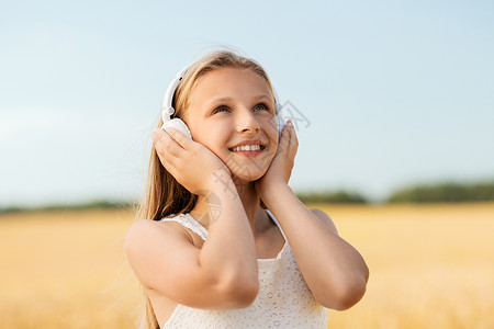 技术人的快乐女孩的肖像耳机谷物领域听音乐夏天夏天谷物地里戴耳机的快乐女孩背景图片