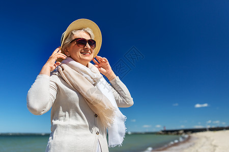 人休闲爱沙尼亚海滩上戴太阳镜草帽的快乐老妇女的肖像快乐的高级女人戴着太阳镜帽子海滩上退休高清图片素材