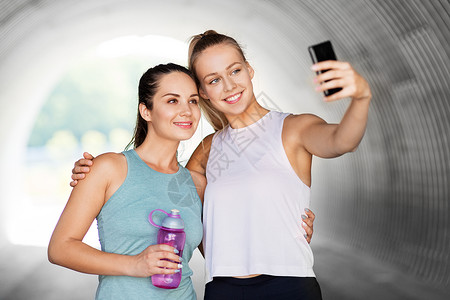 健身,运动健康的生活方式微笑的轻妇女女朋友户外智能手机自拍运动女户外用智能手机自拍背景图片