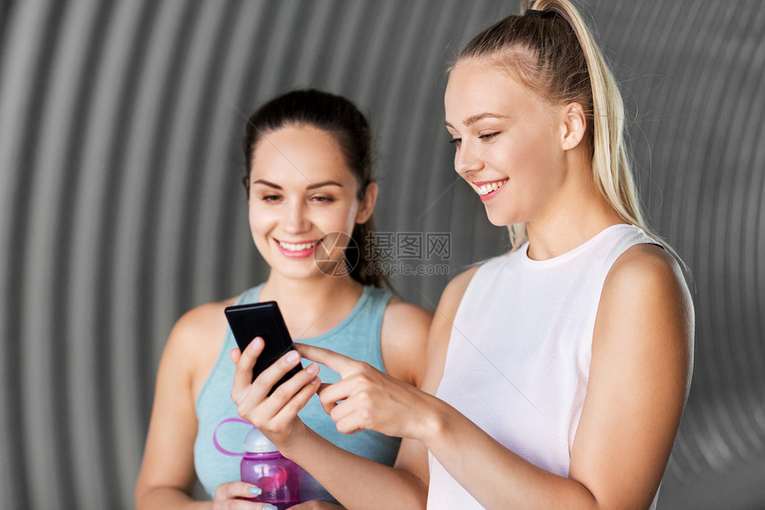 健身,运动健康的生活方式微笑的轻妇女女朋友与智能手机烧瓶智能手机瓶子的女女朋友图片