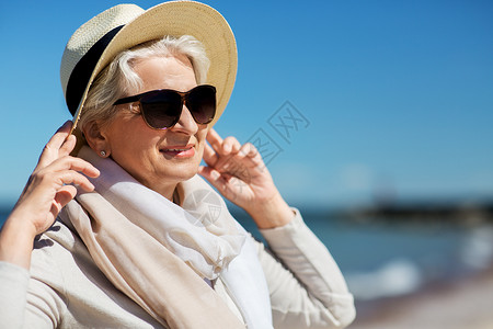 人休闲爱沙尼亚海滩上戴太阳镜草帽的快乐老妇女的肖像快乐的高级女人戴着太阳镜帽子海滩上户外高清图片素材