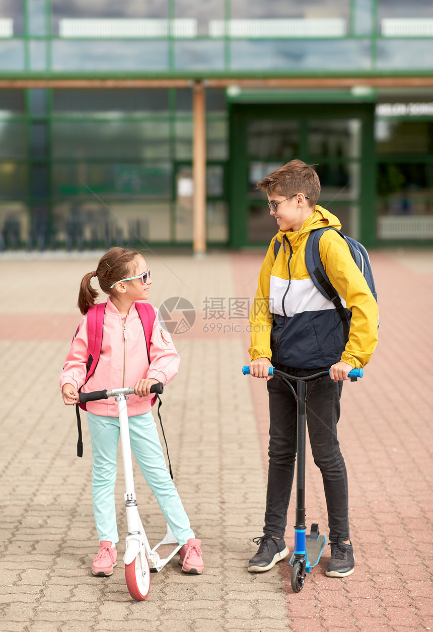 教育,童人的快乐的学校孩子与背包滑板车户外交谈带背包滑板车的快乐学校孩子图片