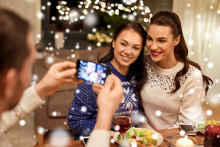 节日庆祝快乐的朋友家里吃诞晚餐,用智能手机雪地上拍照朋友们吃诞晚餐拍照图片