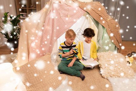 童,诞节友谊的快乐的男孩阅读书与火炬灯孩子帐篷帐篷家里的雪快乐的男孩家孩子们的帐篷里看书背景图片