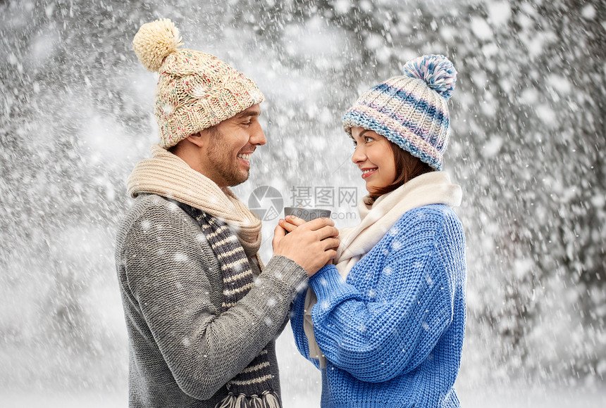 人们,诞节爱情的幸福的浪漫夫妇戴着针帽围巾,雪地背景下着杯穿着冬天衣服的幸福夫妇着杯图片