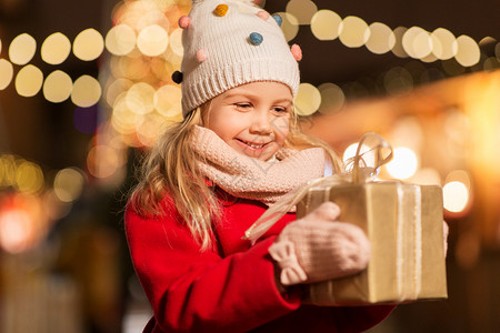 假期,童人的快乐的小女孩与礼品盒诞节市场冬季晚上诞市场上带礼品盒的快乐女孩背景图片