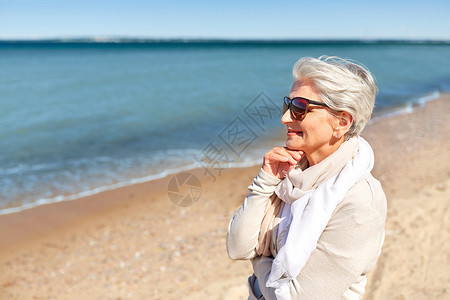人休闲爱沙尼亚海滩上戴太阳镜围巾的快乐老妇女的肖像海滩上戴太阳镜的高级女人的肖像微笑高清图片素材