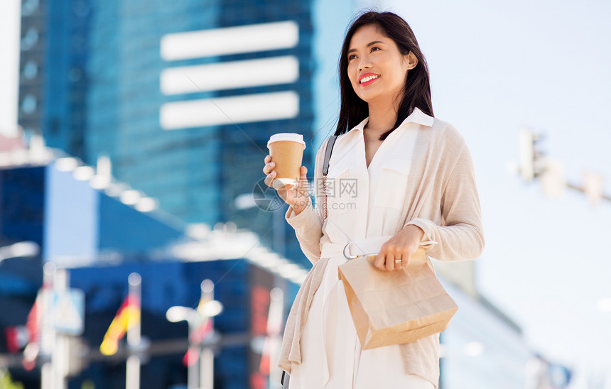 城市街道快乐微笑的女人带着咖啡与午餐图片