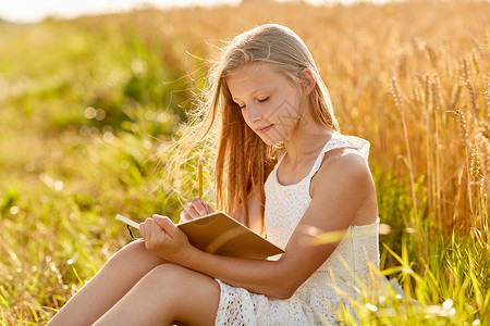乡村,文学休闲微笑的轻女孩穿着白色连衣裙写日记绘画素描夏天的谷物领域微笑的女孩谷物地里写日记背景图片