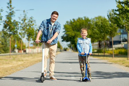 滑板车儿童家庭,休闲父亲的快乐的父亲花时间小儿子骑滑板车城市父亲小儿子城里骑滑板车背景