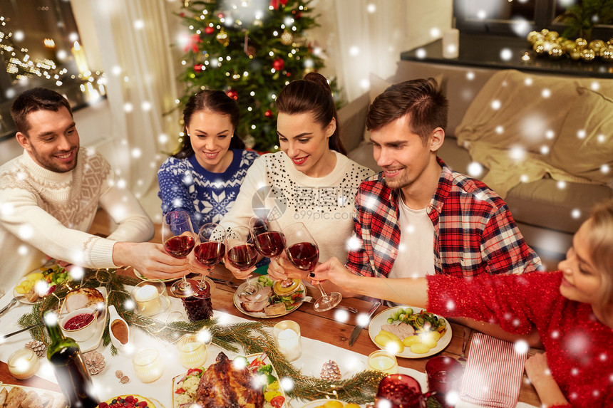 节日庆祝快乐的朋友家里吃诞晚餐,喝红酒,雪地上碰杯朋友们庆祝诞节喝酒图片