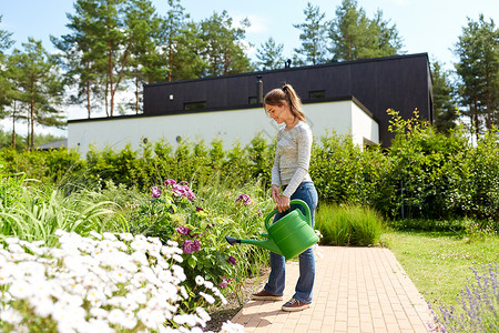 园艺人们的快乐的轻妇女园丁夏季花园浇花轻的女人花园里浇花图片