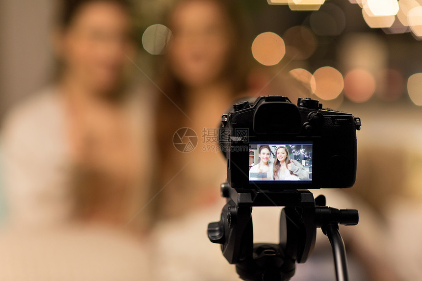 博客,技术,潮格睡衣的快乐的女朋友十几岁的博主与相机录制视频家里女博客作者用相机录制家庭视频图片