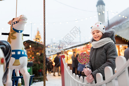 假期,童人的快乐的小女孩与大棒棒糖诞节市场诞节市场上棒棒糖的女孩背景图片