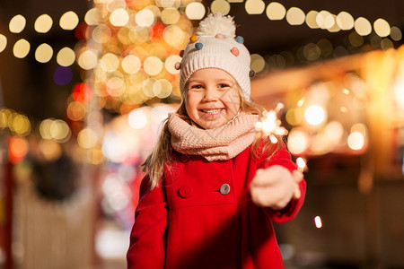 假期,童人的快乐的小女孩与火花诞市场冬季晚上快乐的女孩与火花诞节市场背景图片
