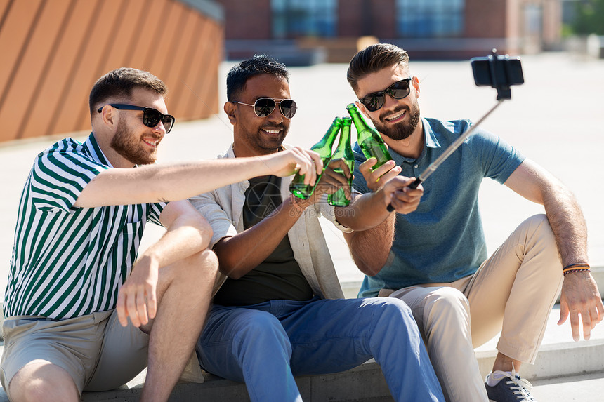 休闲技术人的快乐的男朋友自拍杆上用智能手机拍照,夏天街上品尝啤酒男人品尝啤酒,用智能手机自拍图片