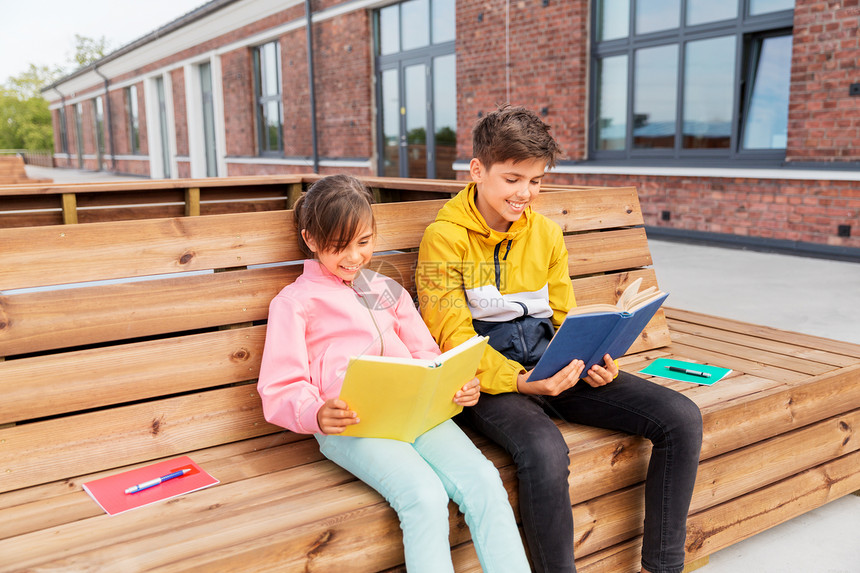 教育,童人的快乐的学校孩子兄妹阅读书籍,坐木制的街道长凳户外学校的孩子们坐长凳上看书图片