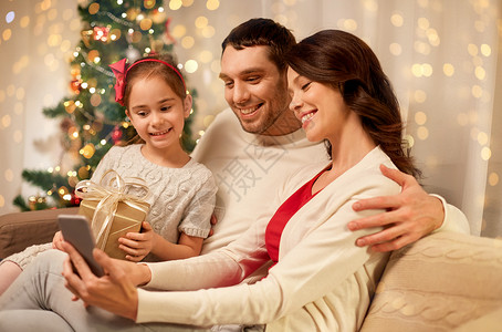 诞节,假期家庭快乐的父亲,小女儿母亲家里智能手机诞节家里智能手机的家庭图片